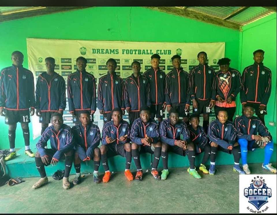 Players in academy tracksuits posing for a group photo in front of a Dreams Football Club banner