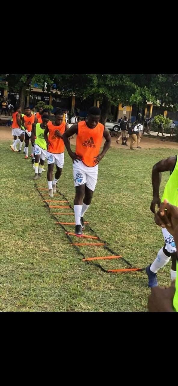 Players in orange bibs performing agility ladder drills on a grass pitch